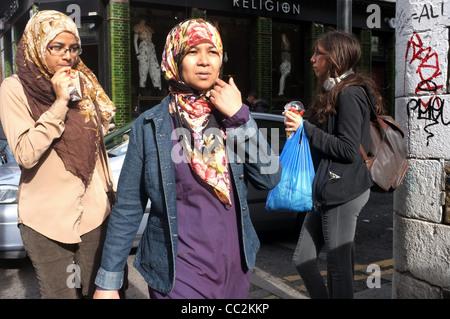 Due giovani donne musulmane, in testa sciarpe, camminare lungo la Brick Lane, London's storica East End. Foto Stock