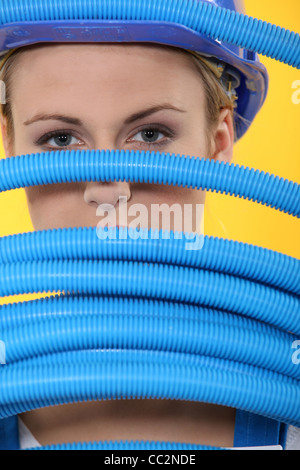 Costruzione femmina lavoratore spiata attraverso tubi corrugati Foto Stock
