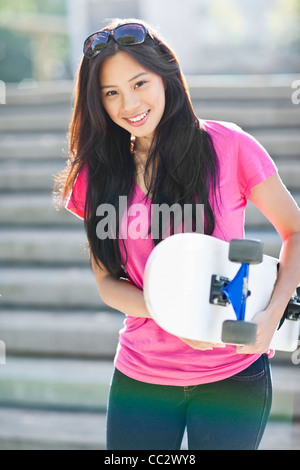 Stati Uniti d'America, Washington, Seattle, giovane donna asiatica in posa con lo skateboard Foto Stock