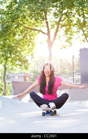 Stati Uniti d'America, Washington, Seattle, Allegro giovane donna seduta su skateboard Foto Stock