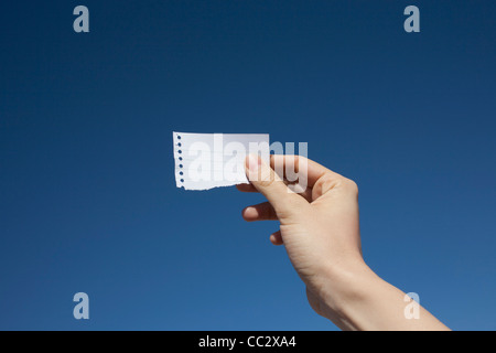 Stati Uniti d'America, Arizona, Winslow, mano di donna che mantiene la carta nota contro il cielo blu Foto Stock