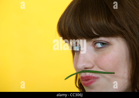 Donna che mantiene un fagiolo verde tra le sue labbra e il suo naso Foto Stock