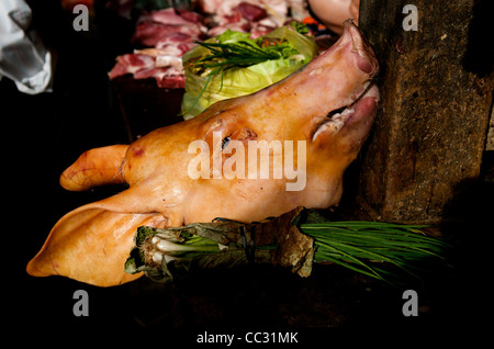 La crudeltà sugli animali e soleggiate del maiale testa & cipolline in un mercato all'aperto, Kampot Mercato, Kampot, Cambogia, sud-est asiatico. Credito: Kraig Lieb Foto Stock