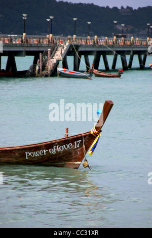 Un longtail barca da pesca è legato vicino a un lungo molo in Chalong Bay, Isola di Phuket, Tailandia. Foto Stock