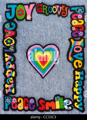 Ricamo su ferro patch multicolore di amore, pace, Felice parole con cuori su un denim jean sfondo Foto Stock