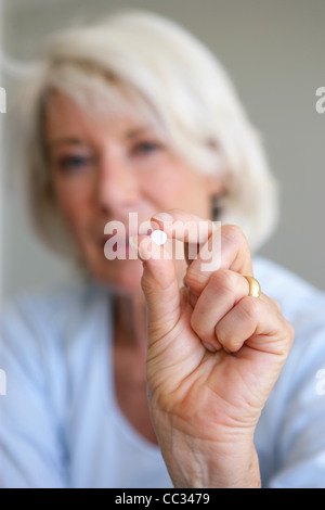 Donna anziana tenendo una pillola Foto Stock