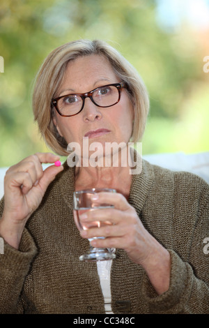 Una vecchia donna di prendere una pillola. Foto Stock