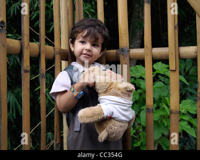 Little Boy di razza mista a giocare con i tradizionali orsacchiotto nella sua casa nel piccolo villaggio in java indonesia Foto Stock