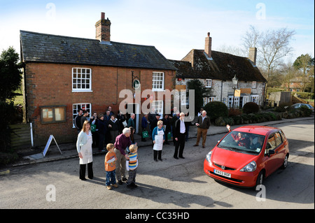 I clienti e il personale presso l'apertura di una comunità su shop nel Wiltshire villaggio di Avebury REGNO UNITO - un passaggio ben onde wisher Foto Stock