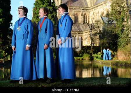 Tre boy coristi dalla Cattedrale di Wells coro in Somerset ripassando all'aperto per Natale carol servizi tramite "pozzi" Foto Stock