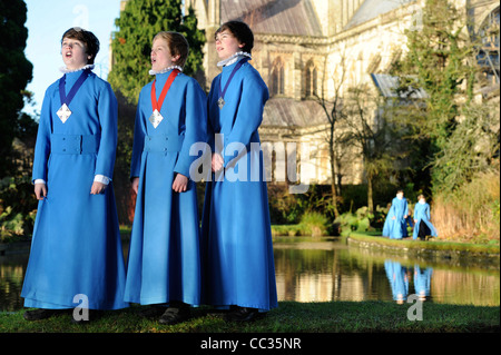 Tre boy coristi dalla Cattedrale di Wells coro in Somerset ripassando all'aperto per Natale carol servizi tramite "pozzi" Foto Stock