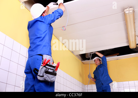 Due elettricista ispezione pannelli a soffitto Foto Stock