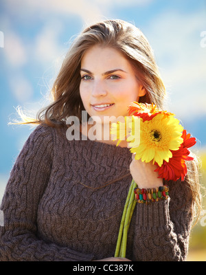 Bella giovane donna con fiori di trascorrere una splendida giornata all'aperto. Foto Stock