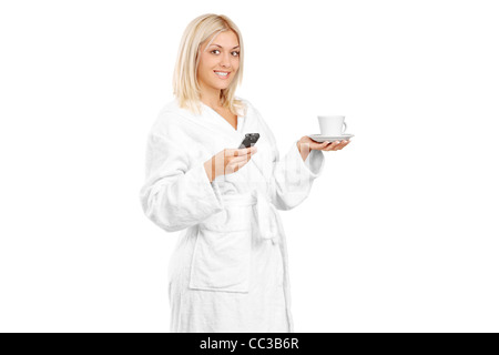 A piena lunghezza Ritratto di una giovane donna in accappatoio tenendo una tazza di caffè e telefono cellulare Foto Stock