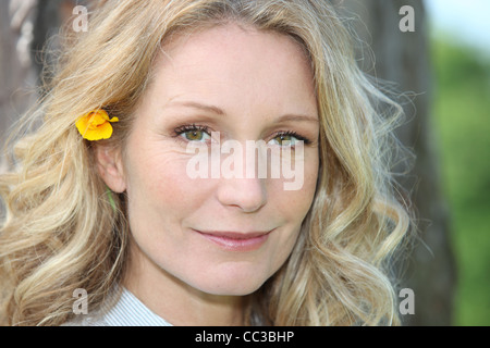 Donna bionda con fiore nei capelli Foto Stock