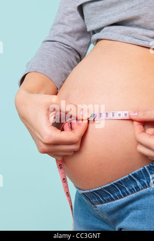 Foto di una settimana 32 preganant donna misurando il suo ventre con un metro a nastro. Foto Stock