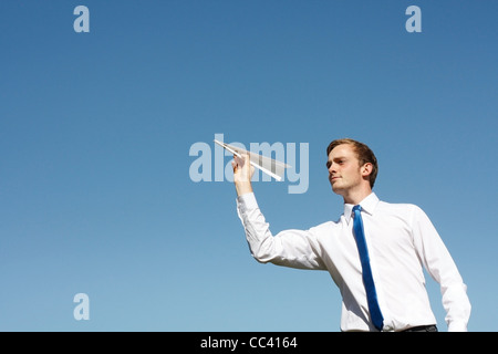 Un uomo di affari di gettare un aeroplano di carta Foto Stock