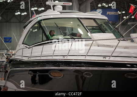 I potenziali acquirenti e persone solo navigando controllare le barche a motore al Progressive Insurance New York Boat Show Foto Stock