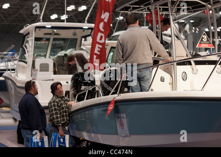 I potenziali acquirenti e persone solo navigando controllare le barche a motore al Progressive Insurance New York Boat Show Foto Stock