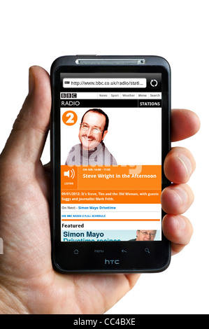 Ascolto di radio della BBC 2's Steve Wright nel pomeriggio in streaming su uno smartphone HTC Foto Stock