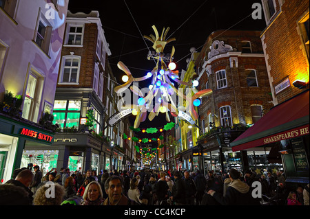 Carnaby Street piena di Natale gli amanti dello shopping a Londra, Inghilterra, Regno Unito, con la festa delle luci decorative di notte Foto Stock