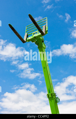 Green telescopico idraulico forche torreggianti contro il luminoso cielo blu Foto Stock