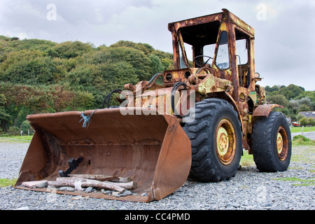 Grande vecchio arrugginito Digger utilizzato per la cancellazione della spiaggia ghiaiosa Foto Stock