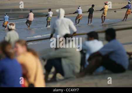 Fotografia di Roy Riley pescatori scacciando le loro reti sulla spiaggia a Kovalam in Kerala, India Foto Stock