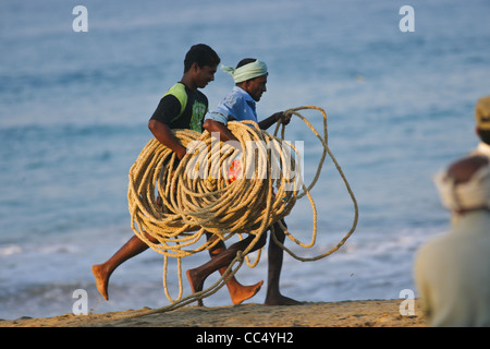 Fotografia di Roy Riley pescatori scacciando le loro reti sulla spiaggia a Kovalam in Kerala, India Foto Stock