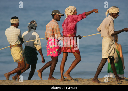Fotografia di Roy Riley pescatori scacciando le loro reti sulla spiaggia a Kovalam in Kerala, India Foto Stock