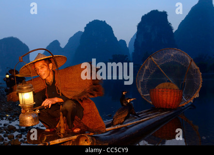 Cormorano pescatore lampada di illuminazione con gli uccelli sulla zattera di bambù all'alba con ambiente carsico picchi sulla riva del fiume Li Yangshuo Cina Foto Stock