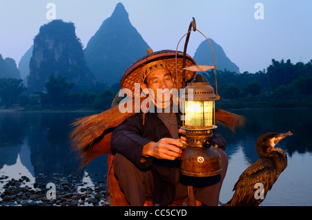 Cormorano pescatore lanterna di illuminazione con bird su zattera di bambù all'alba sulla riva del fiume Li con ambiente carsico picchi Yangshuo Cina Foto Stock