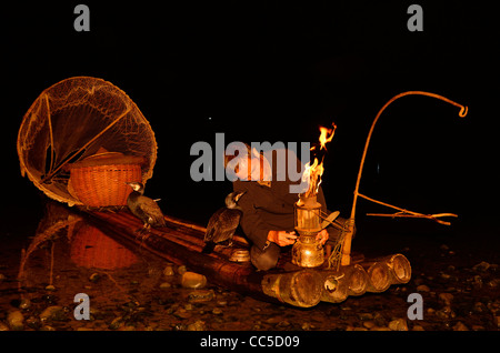 Cormorano illuminazione pescatore la sua lanterna sul fiume Li Yangshuo Cina in inizio di mattina di oscurità Foto Stock