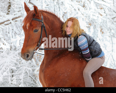 Blonde 22-anno del modello con il suo cavallo in un paesaggio di neve,concentrarsi sulla ragazza Foto Stock