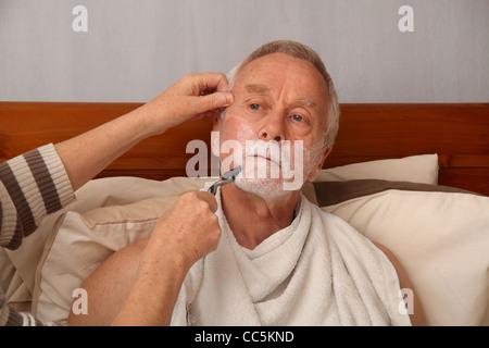 Un bedbound l uomo nella sua 60's rasata da sua moglie/accompagnatori Foto Stock
