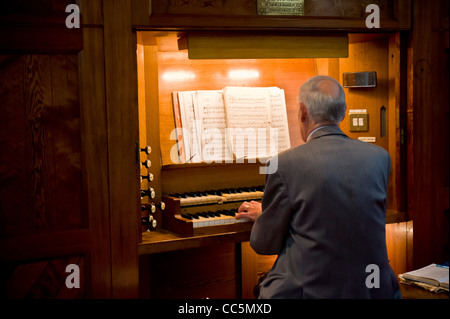 Vista posteriore di un anziano maschio caucasico che gioca l'organo in una chiesa del Regno Unito. Foto Stock