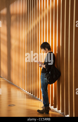 Giappone, Tokyo, Roppongi, Tokyo National Art Center, Vista interna del giovane uomo utilizzando il telefono cellulare Foto Stock