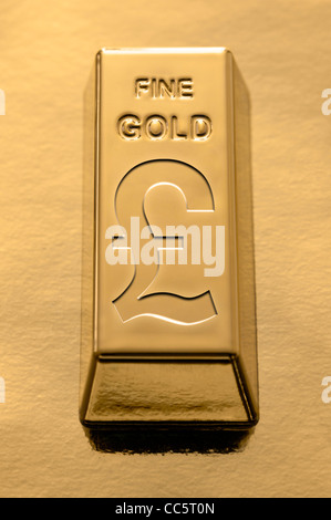 Gold bar con un sterling pound simbolo impresso su di esso su un fondo dorato Foto Stock
