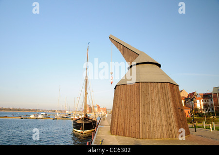 L uomo medievale-powered gru di carico e la barca a vela nel porto storico, città anseatica di Rostock, Germania Foto Stock