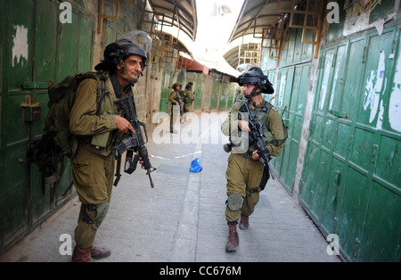 Soldati israeliani in pattuglia nella città vecchia di Hebron per accompagnare un gruppo di coloni ebrei. Foto Stock