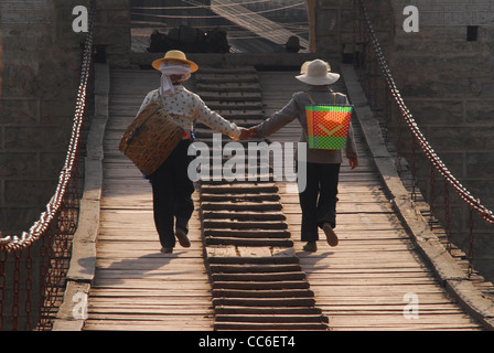 Yi donne camminando sul Ponte Yunlong mano nella mano, Yangbi, Dali, Yunnan , Cina Foto Stock