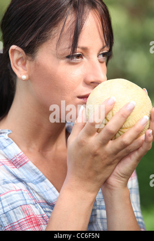 Giovane donna odorare un melone Foto Stock