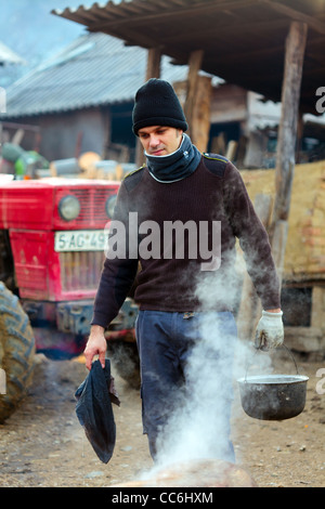Giovane uomo rurale all'aperto in inverno con una pentola di acqua bollente Foto Stock