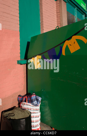 Sacchetti di abbigliamento di seconda mano sinistra in prossimità di una carità shop recipiente in una strada di Londra. Foto Stock