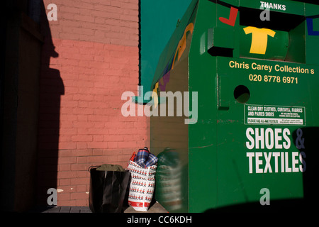 Sacchetti di abbigliamento di seconda mano sinistra in prossimità di una carità shop recipiente in una strada di Londra. Foto Stock