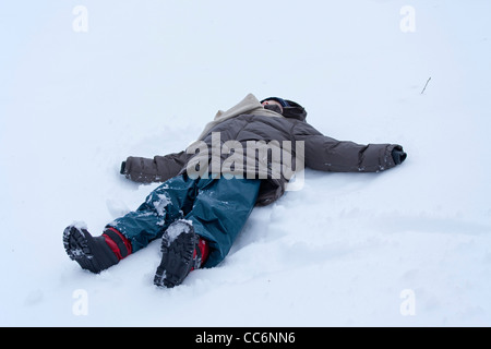 Ragazzo giovane rendendo un angelo di neve a Kahler Asten vicino a Winterberg, Sauerland, Renania settentrionale-Vestfalia, Germania Foto Stock