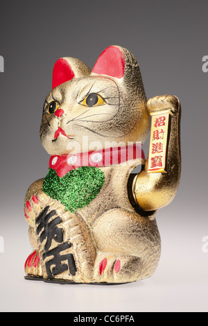 Maneki Neko, il fatto cenno cat - giapponese di buona fortuna fascino, con sbandieratori paw braccio. Fatta cinese ornamento. Foto Stock