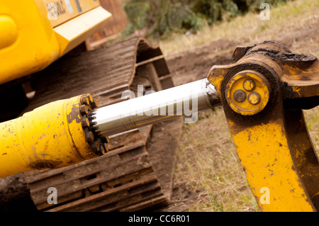 Un cilindro idraulico dipinto di giallo con un asta di cromo Foto Stock