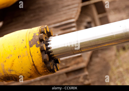 Un cilindro idraulico dipinto di giallo con un asta di cromo Foto Stock