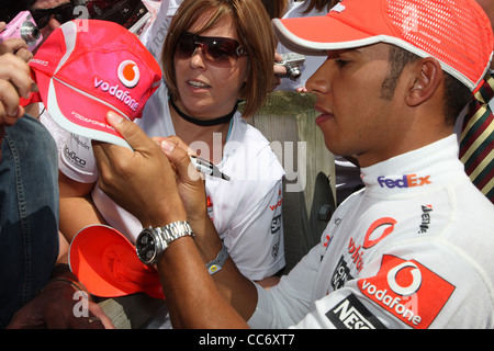 Lewis Hamilton Formula Uno motor racing driver segni un fans Vodaphone cap. Foto Stock